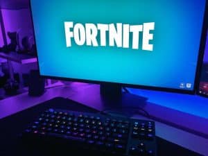 black flat screen computer monitor with black computer keyboard - Fortnite game loading on a gaming setup., tags: onlinespil - unsplash