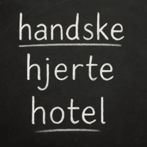 Nærbillede af sort kridttavle med hvide eksempler på danske ord med stumt h som ’handske’, ’hjerte’ og ’hotel’.