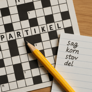 Krydsord med markeret ord ’partikel’, blyant og noter med synonymer og løsningsforslag