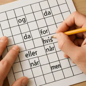 Hænder løser krydsord med blyant, fokus på danske bindeord i felterne
