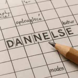 Nærbillede af et dansk DANNELSE-krydsord med synonymer, løsninger og blyant klar ved siden af