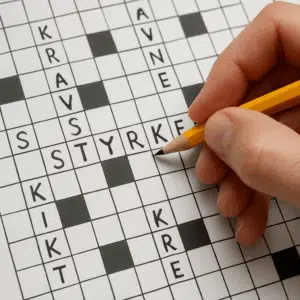 En hånd holder en blyant over et krydsord med ordet "styrke", omgivet af synonymer og løsningsforslag